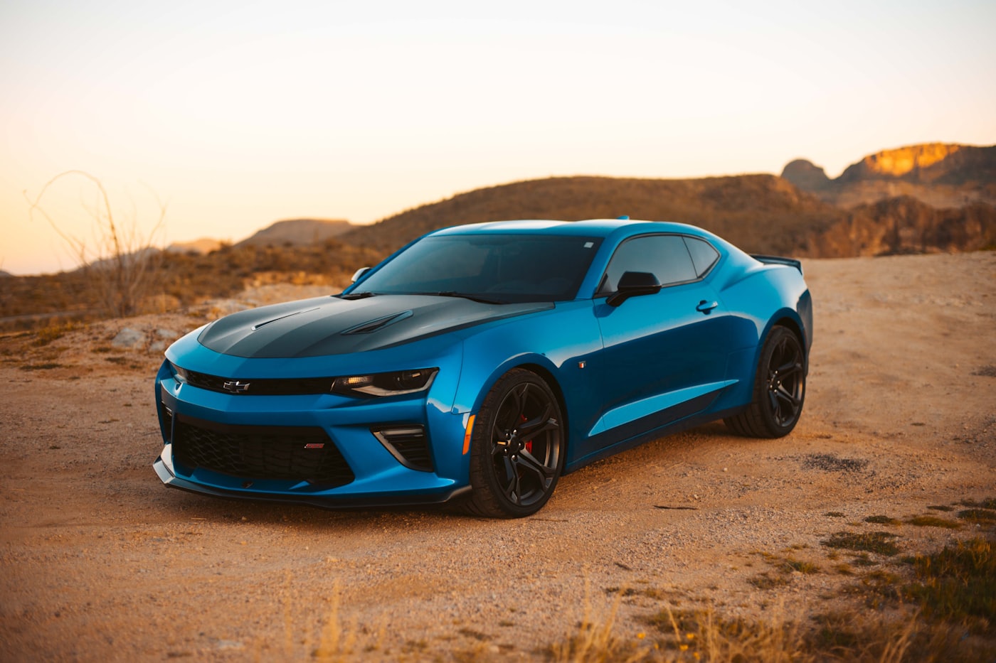 A parked coupé glowing under a warm evening sky
